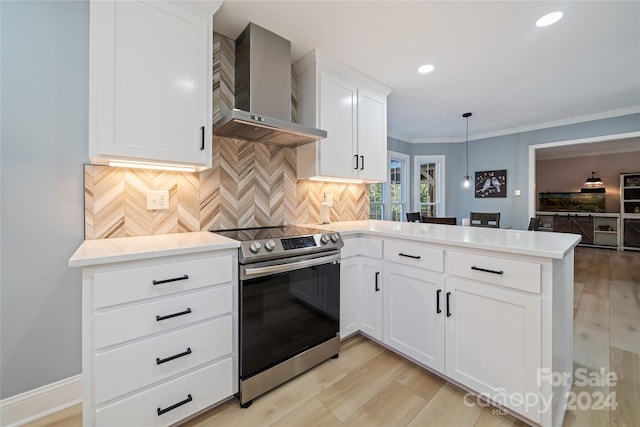 kitchen featuring hanging light fixtures, kitchen peninsula, stainless steel electric range, wall chimney range hood, and white cabinetry