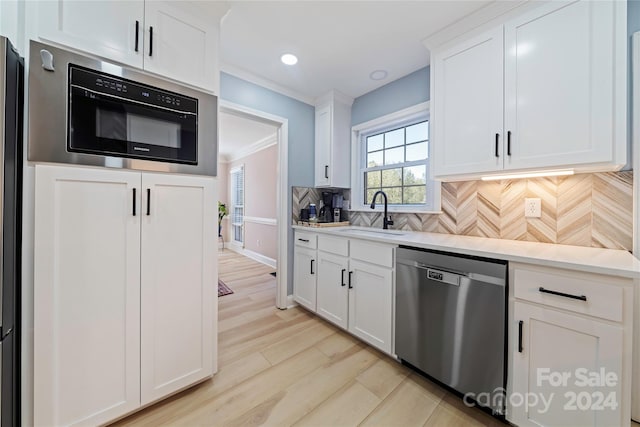 kitchen with white cabinets, backsplash, and stainless steel dishwasher