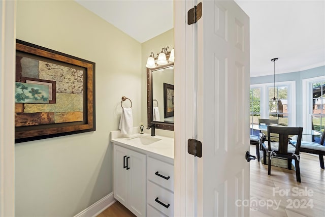 bathroom with ornamental molding, hardwood / wood-style flooring, and vanity