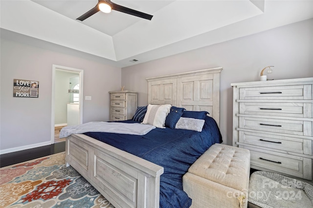 bedroom with ceiling fan, a raised ceiling, and dark hardwood / wood-style flooring