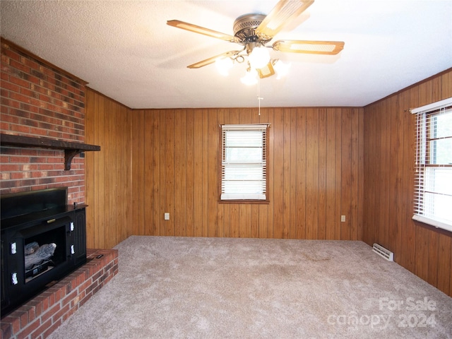 unfurnished living room with carpet flooring, wooden walls, and ceiling fan