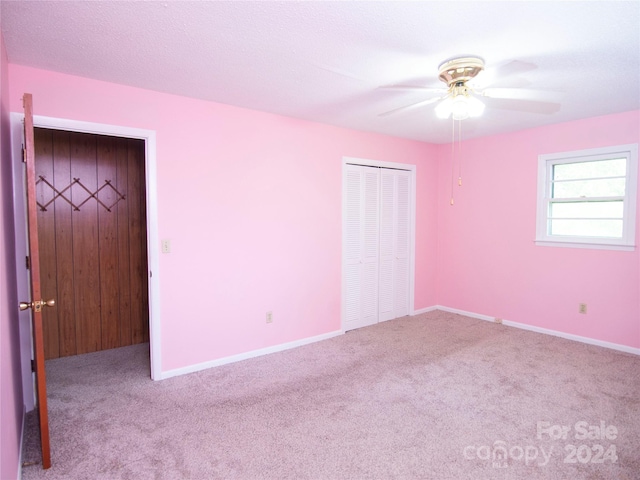 unfurnished bedroom featuring a closet, light colored carpet, and ceiling fan