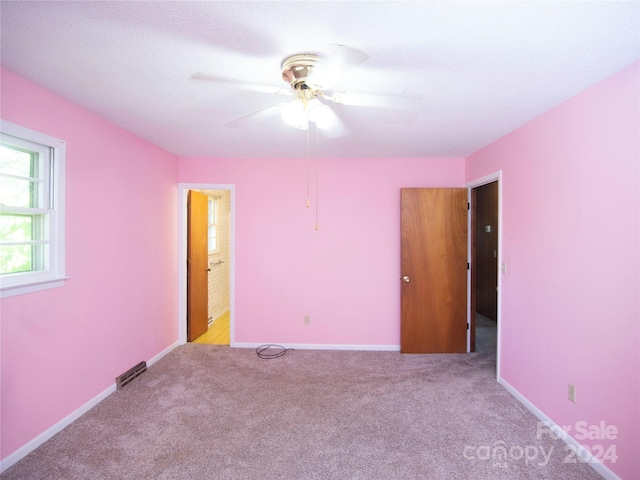 carpeted empty room featuring ceiling fan and a textured ceiling