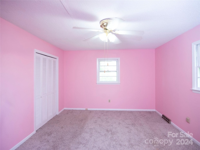 unfurnished bedroom with light carpet, a closet, a textured ceiling, and ceiling fan