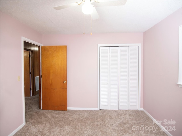 unfurnished bedroom with light carpet, a closet, a textured ceiling, and ceiling fan