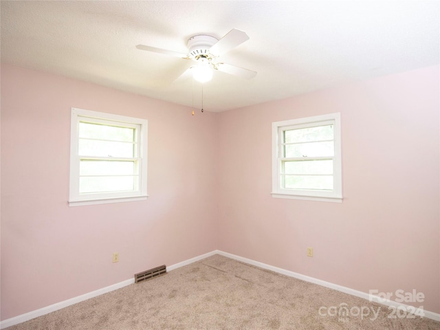 carpeted empty room featuring ceiling fan and plenty of natural light