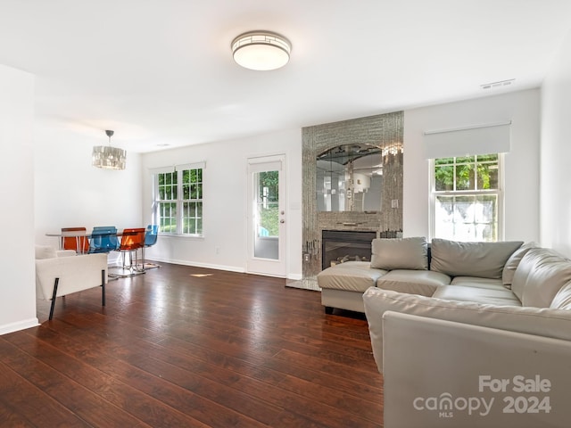 living room with a fireplace, a wealth of natural light, and dark wood-type flooring