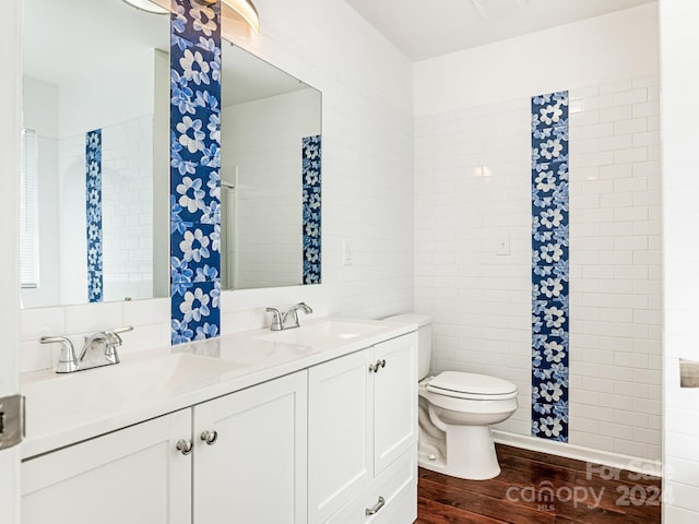 bathroom featuring wood-type flooring, tile walls, vanity, and toilet