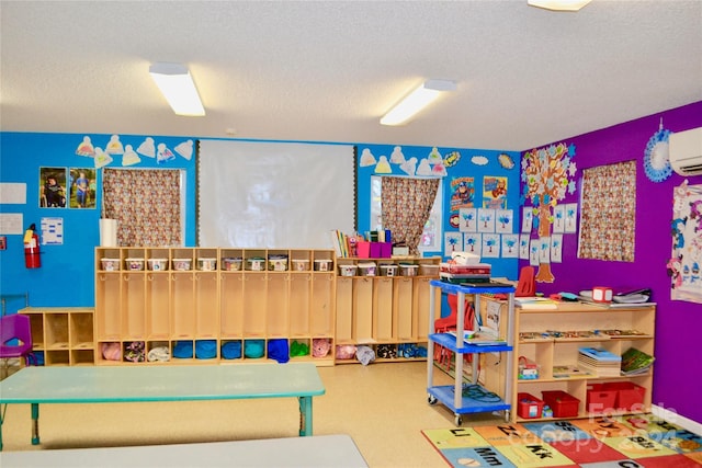 playroom with a wall unit AC and a textured ceiling