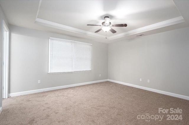 unfurnished room featuring ceiling fan, a tray ceiling, crown molding, and carpet