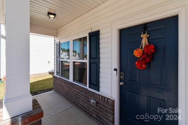doorway to property with brick siding and a porch