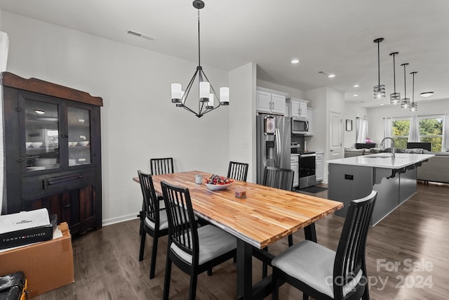 dining area with sink, a chandelier, and dark hardwood / wood-style flooring