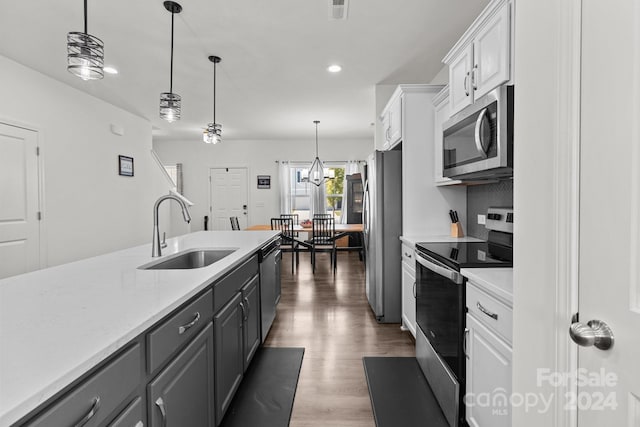 kitchen featuring dark hardwood / wood-style floors, white cabinets, sink, appliances with stainless steel finishes, and decorative light fixtures