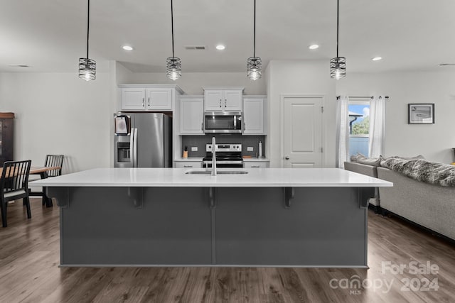 kitchen featuring stainless steel appliances, light countertops, a breakfast bar, and dark wood-type flooring