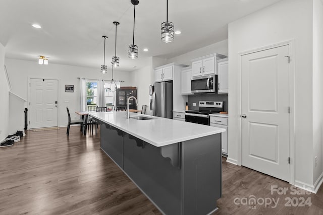 kitchen with white cabinets, sink, a large island, appliances with stainless steel finishes, and a kitchen bar