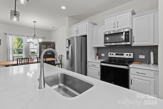 kitchen featuring stainless steel appliances, a sink, an inviting chandelier, white cabinetry, and light countertops