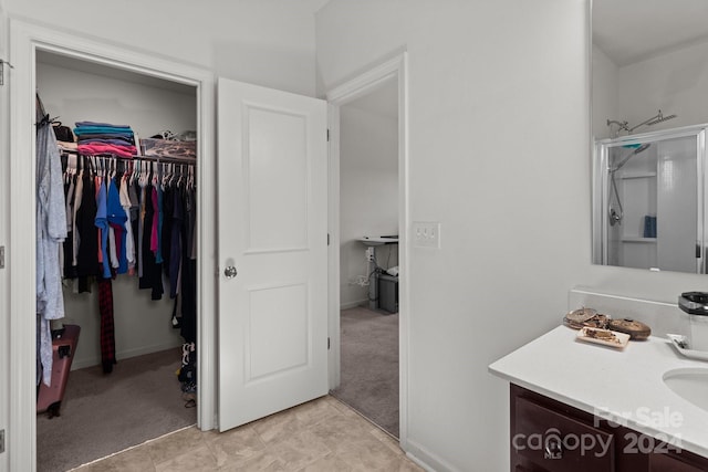 bathroom with a walk in closet, baseboards, and vanity