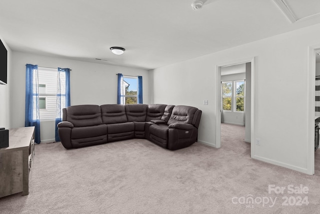 living area featuring light colored carpet, baseboards, and a healthy amount of sunlight