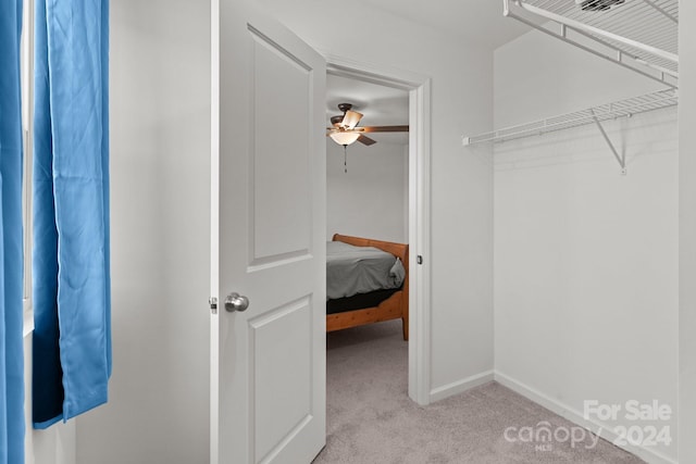 walk in closet with light colored carpet and ceiling fan