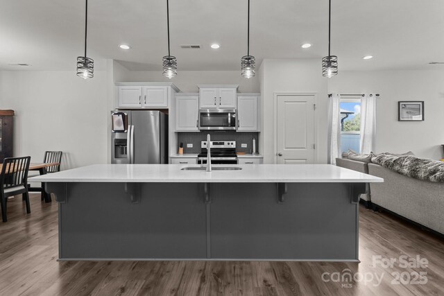1109 Freeman View Dr, Albemarle, NC 28001 - kitchen featuring appliances with stainless steel finishes, light countertops, a kitchen breakfast bar, white cabinetry, and recessed lighting