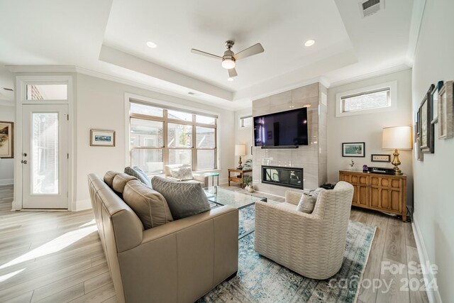 living room featuring a wealth of natural light, a tray ceiling, and light hardwood / wood-style floors