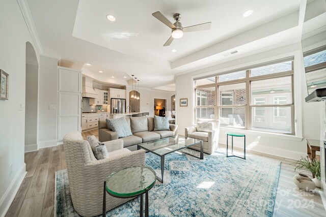 living room with ornamental molding, light wood-type flooring, and ceiling fan