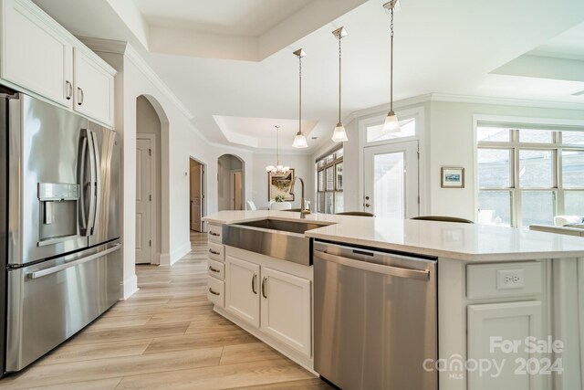 kitchen with appliances with stainless steel finishes, light wood-type flooring, white cabinetry, and a raised ceiling