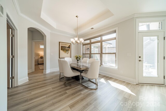 dining space featuring an inviting chandelier, crown molding, hardwood / wood-style floors, and a tray ceiling