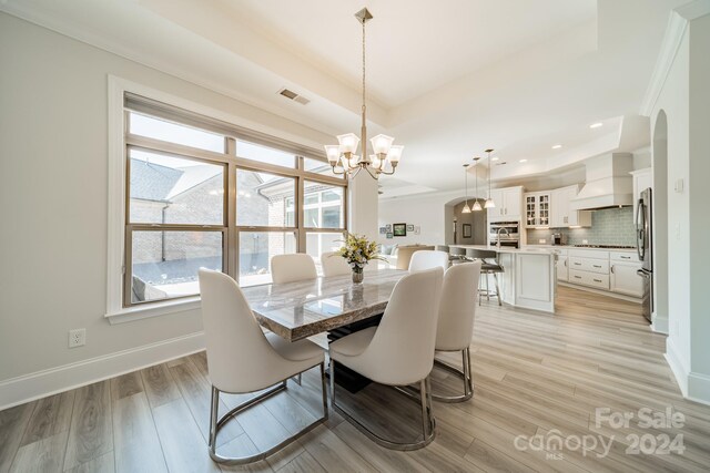 dining space with light hardwood / wood-style floors, a notable chandelier, and crown molding