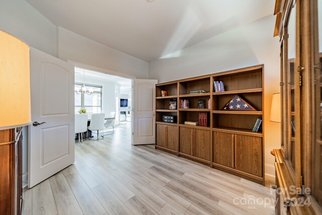 home office with lofted ceiling, a chandelier, and light wood-type flooring