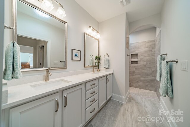 bathroom with vanity, hardwood / wood-style flooring, and a tile shower