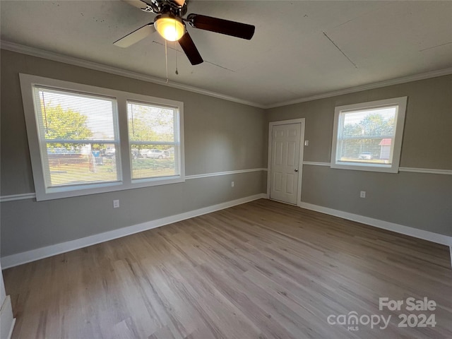 spare room with a wealth of natural light, crown molding, light hardwood / wood-style floors, and ceiling fan