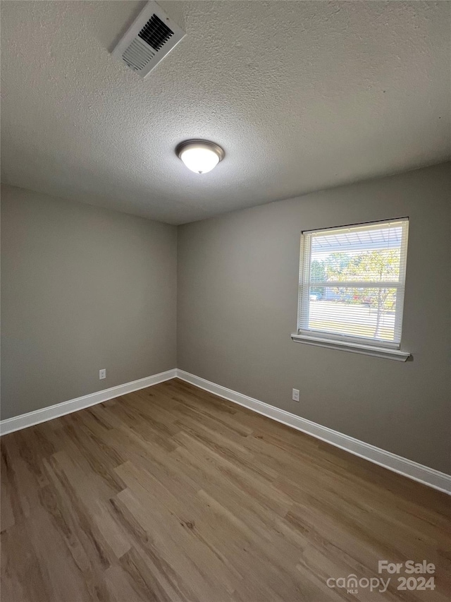 unfurnished room featuring hardwood / wood-style flooring and a textured ceiling