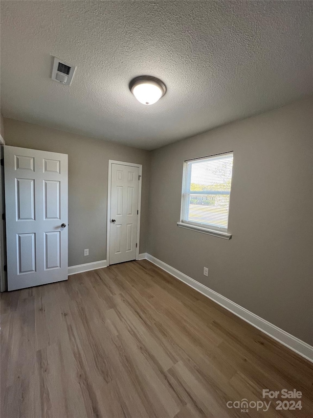 unfurnished bedroom with light hardwood / wood-style flooring and a textured ceiling