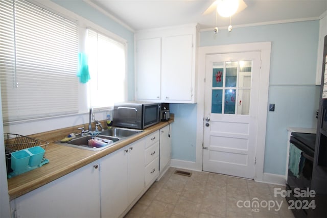 kitchen featuring ceiling fan, sink, and white cabinets