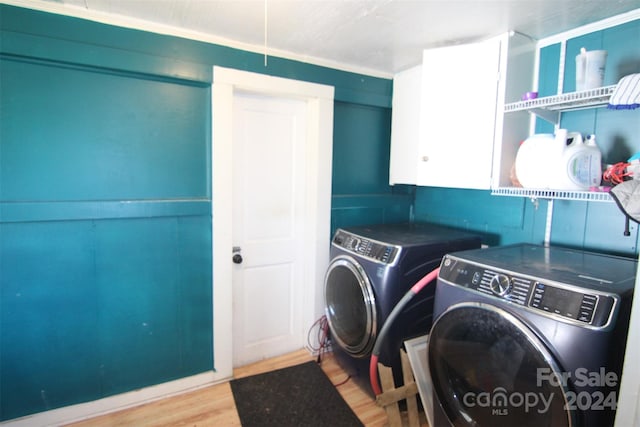 laundry room with washing machine and dryer, hardwood / wood-style flooring, and cabinets