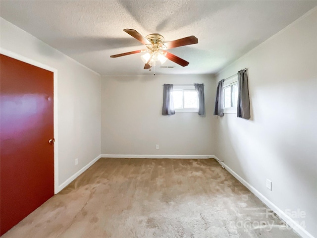 spare room featuring light carpet, ceiling fan, and a textured ceiling