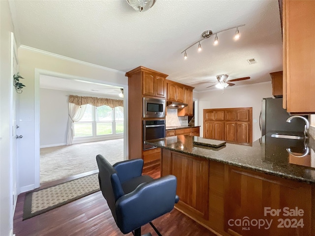 kitchen featuring stainless steel appliances, sink, kitchen peninsula, crown molding, and a textured ceiling