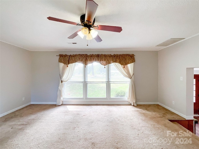 carpeted spare room featuring a textured ceiling and ceiling fan