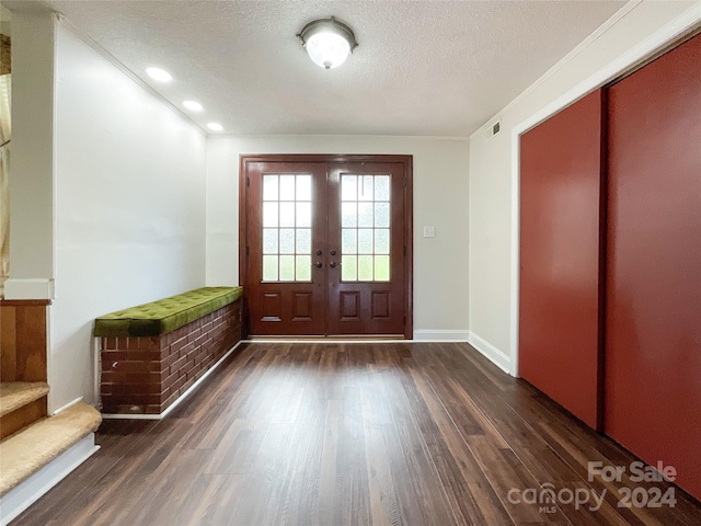 foyer entrance featuring ornamental molding, dark wood-type flooring, and a textured ceiling