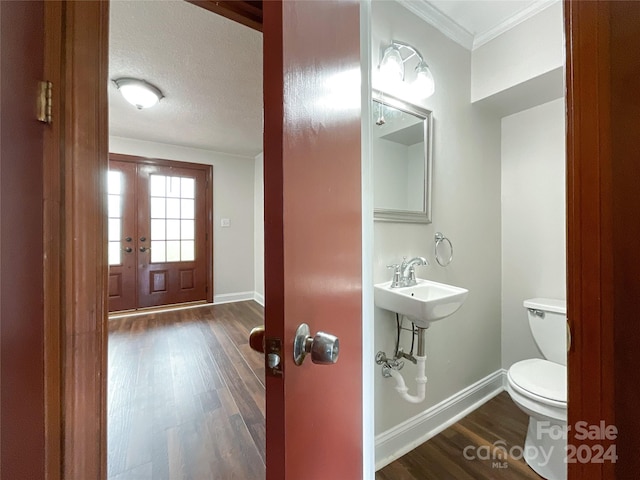 bathroom with hardwood / wood-style flooring, sink, ornamental molding, toilet, and a textured ceiling