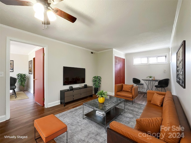 living room with crown molding, dark hardwood / wood-style flooring, a textured ceiling, and ceiling fan