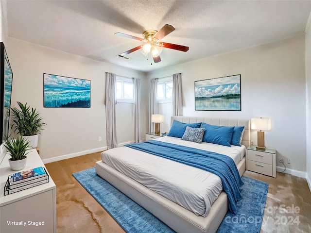 bedroom with light colored carpet, ceiling fan, and a textured ceiling