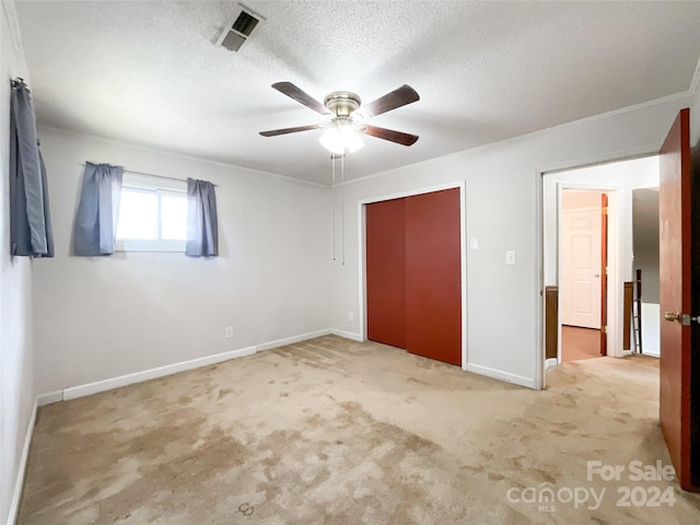 unfurnished bedroom with a textured ceiling, ceiling fan, and light colored carpet