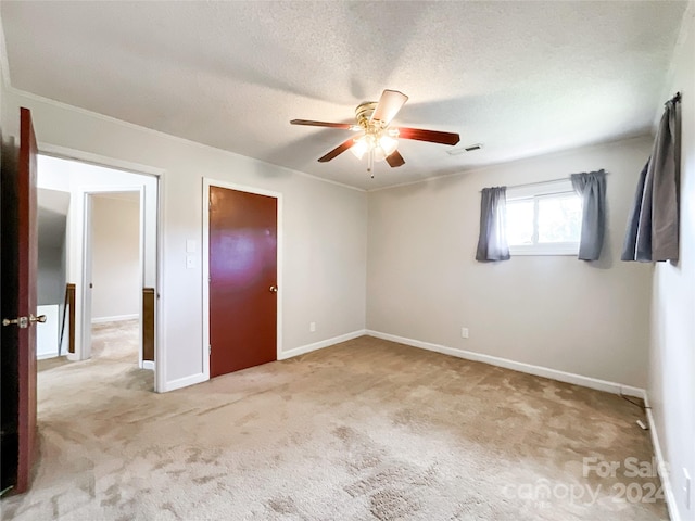 unfurnished bedroom with ceiling fan, a textured ceiling, light carpet, and ornamental molding