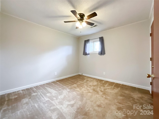 carpeted spare room featuring ceiling fan, a textured ceiling, and ornamental molding