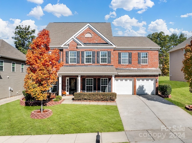 view of front of home with covered porch, a front lawn, and a garage