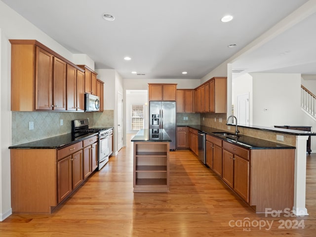 kitchen with sink, light hardwood / wood-style floors, appliances with stainless steel finishes, and a center island