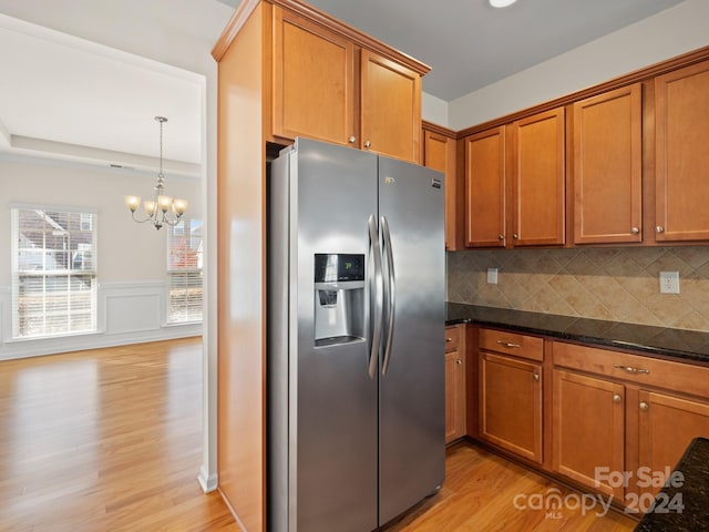 kitchen featuring stainless steel fridge, decorative backsplash, light wood-type flooring, and dark stone counters