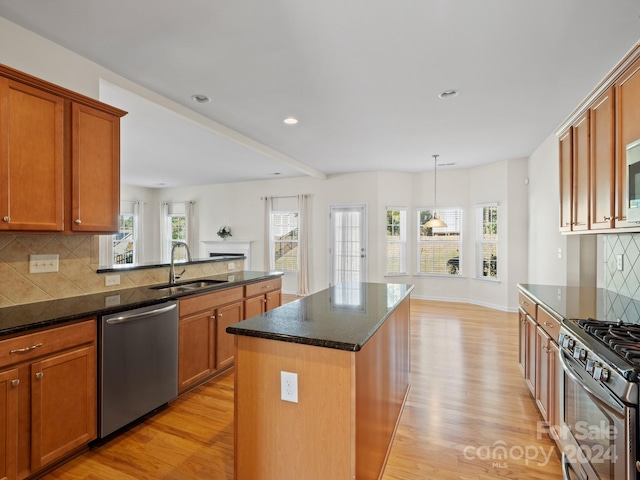 kitchen featuring tasteful backsplash, appliances with stainless steel finishes, light wood-type flooring, sink, and a center island